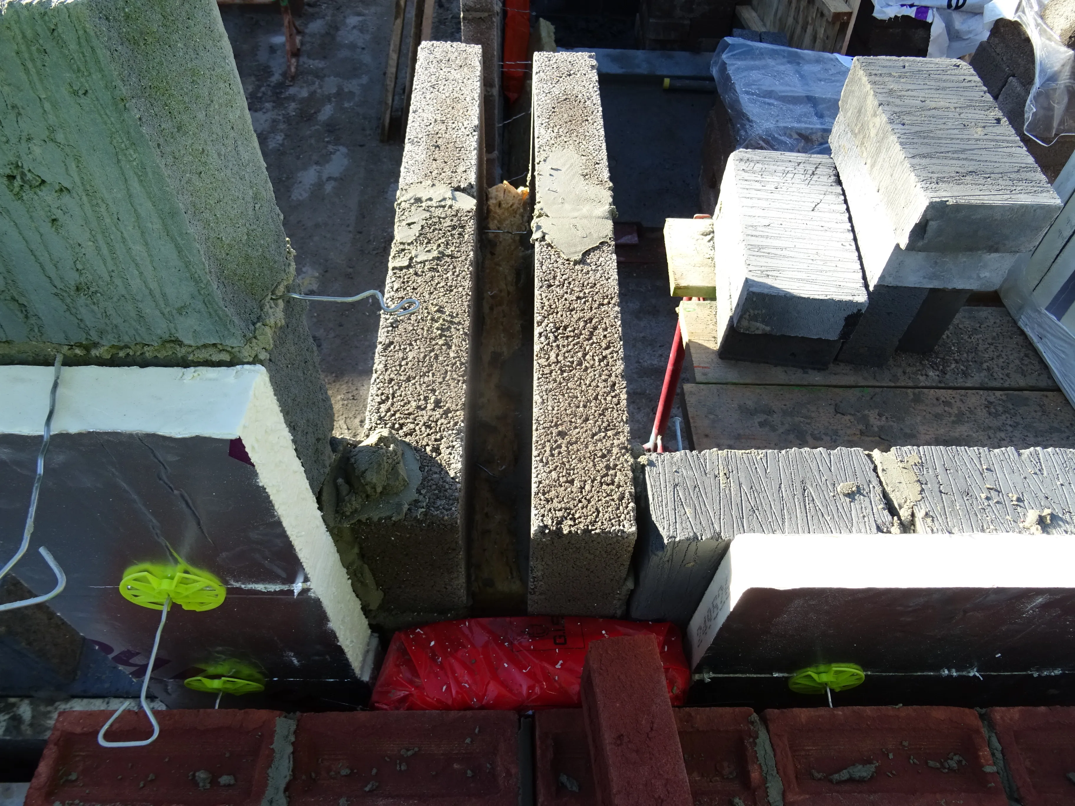 A cavity wall under construction, insulation boards and wall ties on show, the cavity clear
